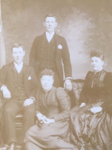 Photo 7: Two seated women, one seated man, one standing man. Photographer: Brockenshire, Beaver Block, Wingham, Ontario.